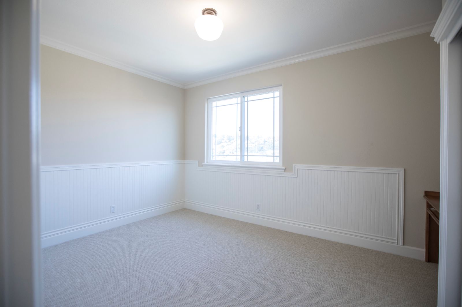 An empty bedroom with light walls and daylight entering through a window