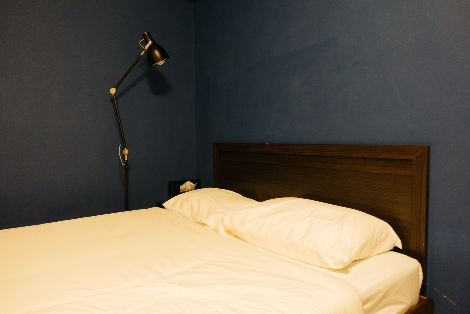 Dark blue bedroom wall seen under a warm adjustable lamp